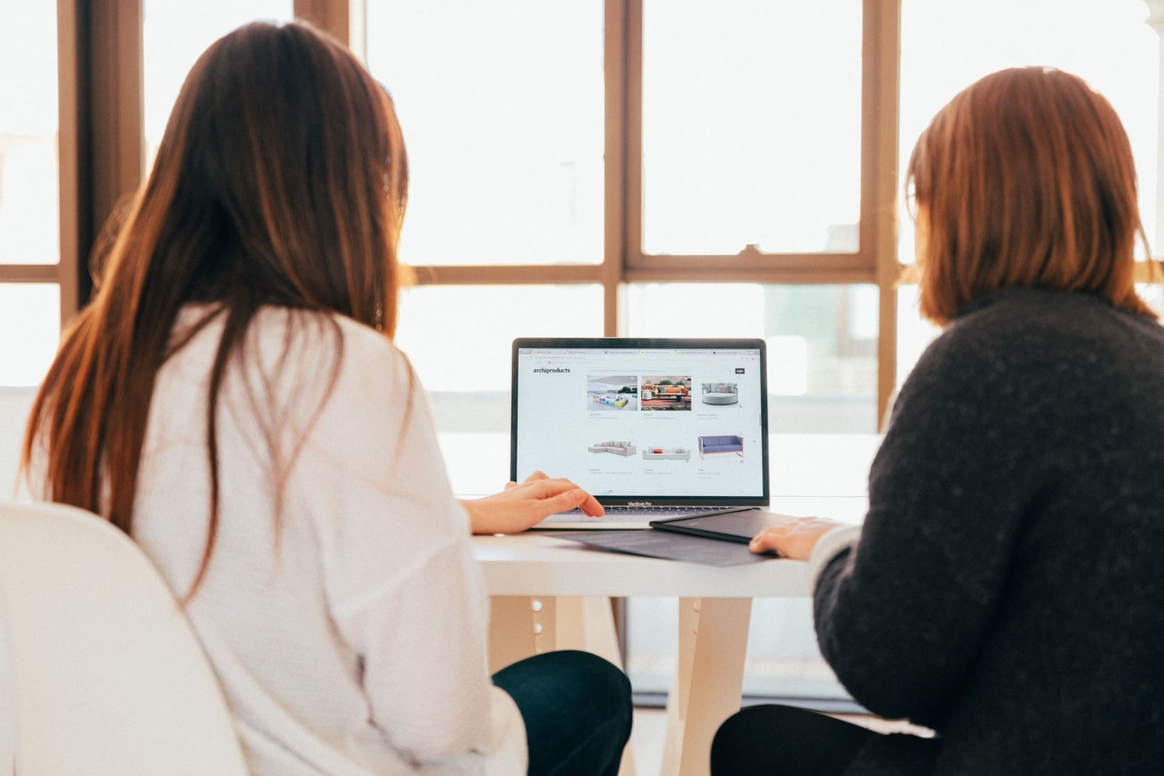 Duas mulheres olhando para o computador, e conversando sobre criação de sites e loja virtual